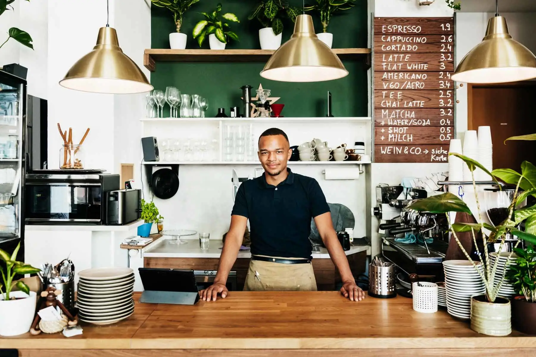 Barista em pé, atrás de um balcão de cafeteria 