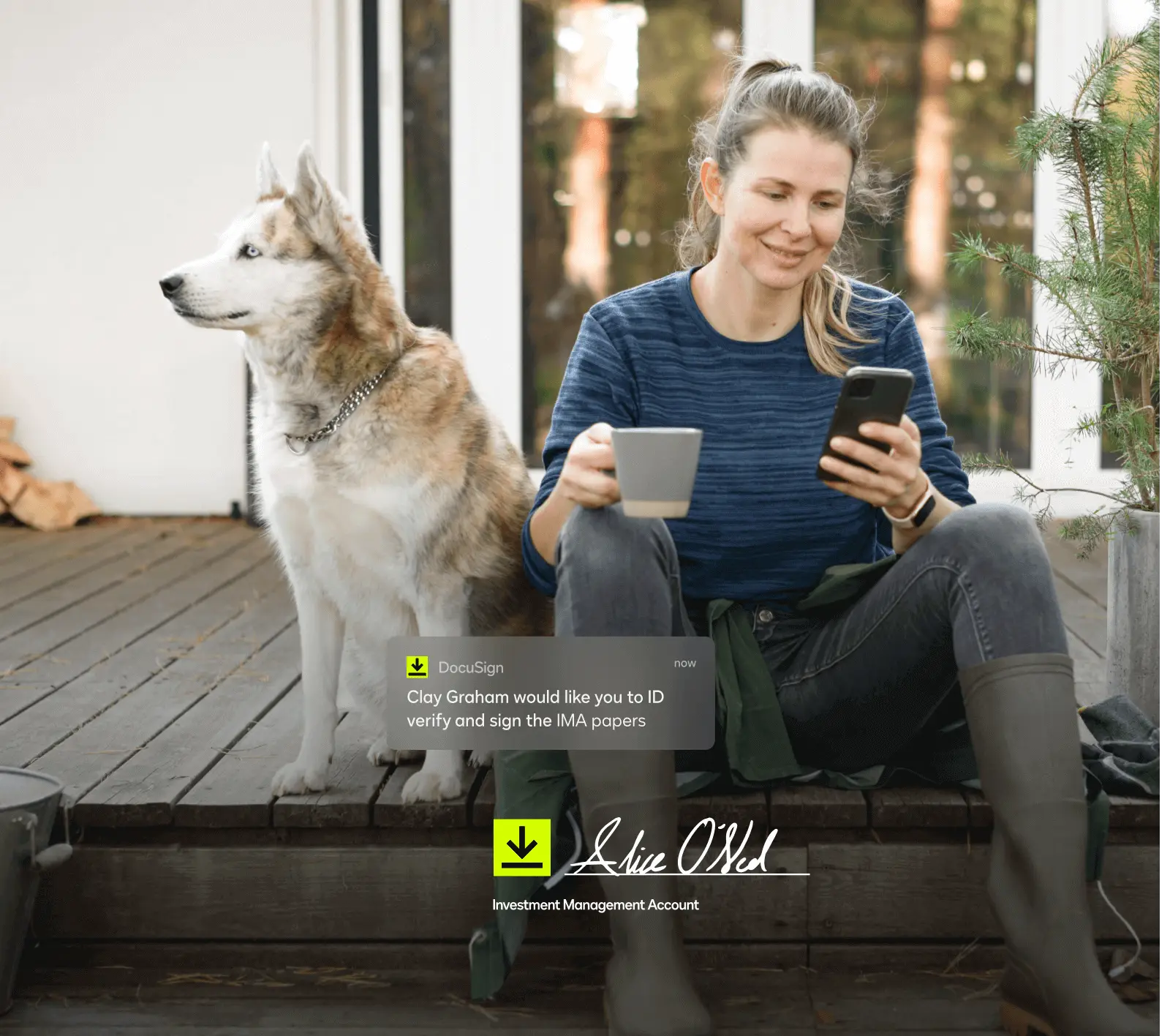 Woman with cup of coffee looking down at her phone next to a dog